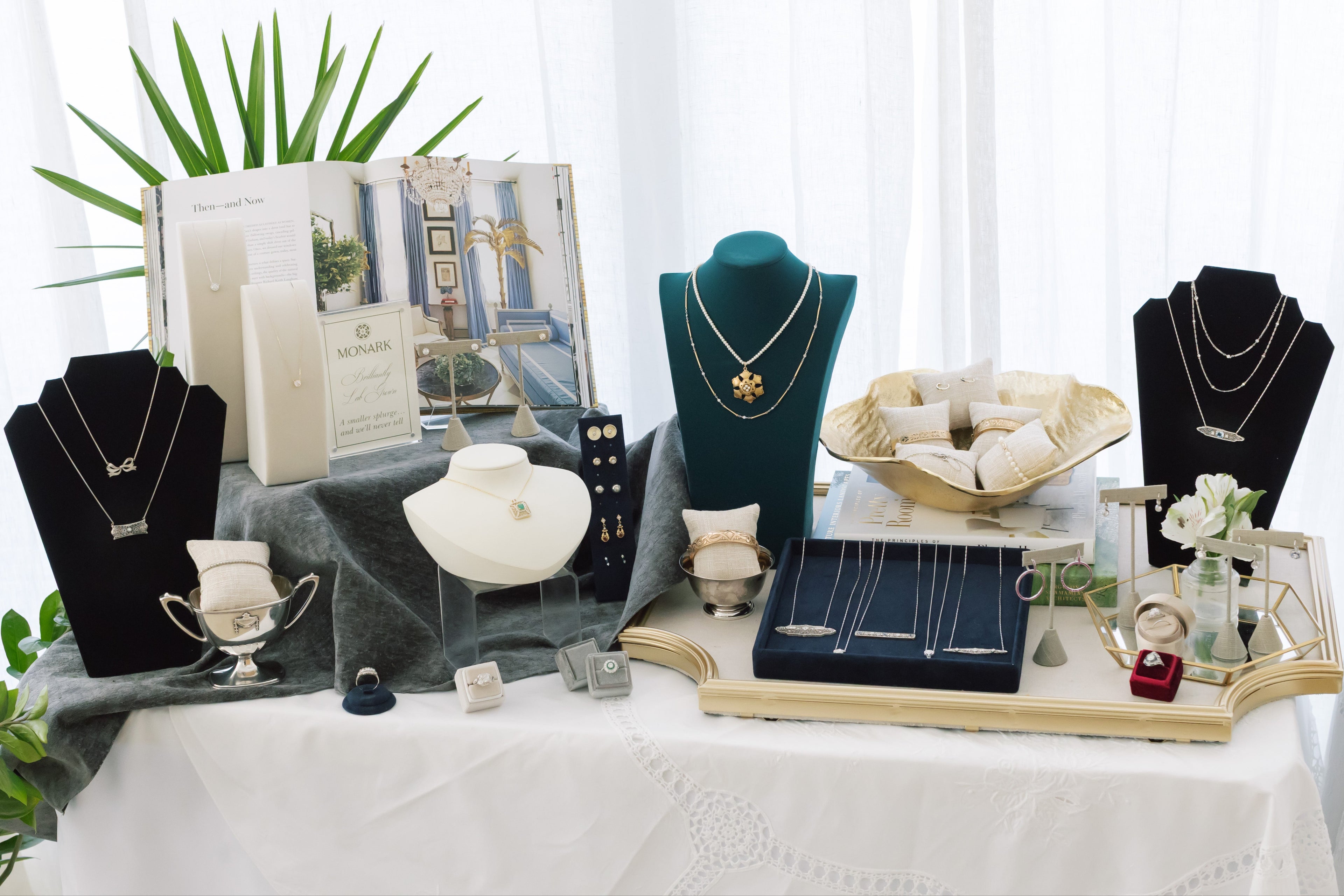 Jewelry display with necklaces on mannequins and decorative items on a table.